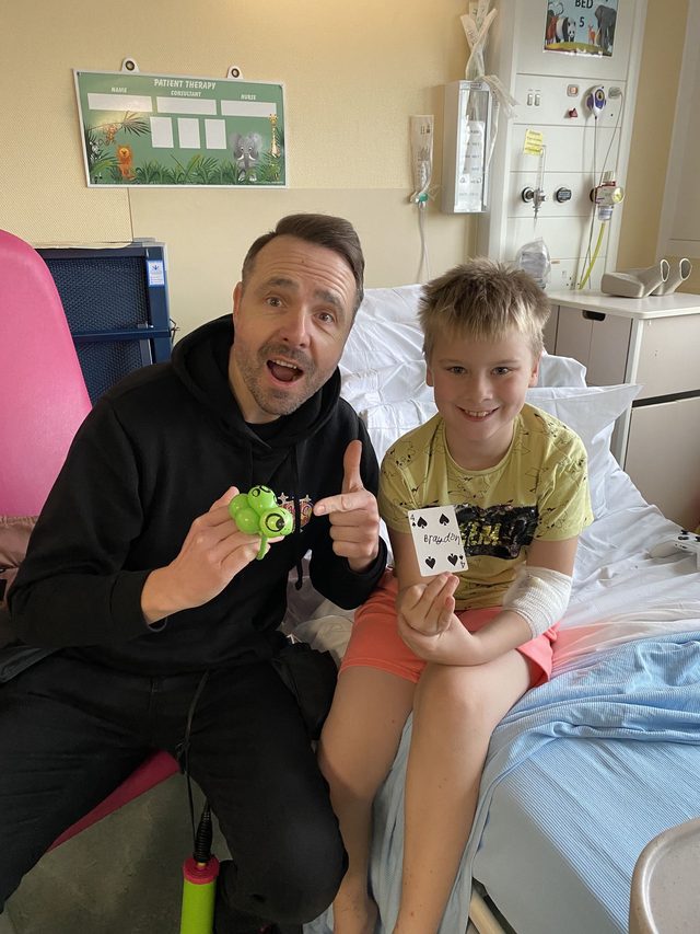 A Pod entertainer performing magic for a smiling young patient
